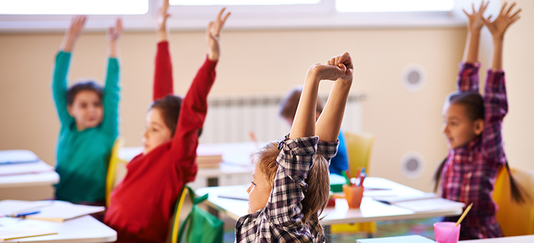 School children stretching up at lesson